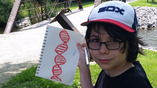 2016 Annual Report image of a boy holding up a notebook.