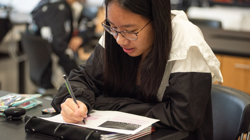 Student writing in a notebook.